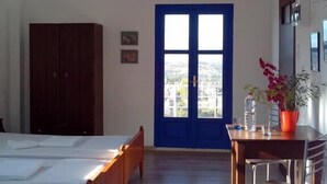 Un dormitorio con cama, un escritorio y silla, un armario y una puerta azul con vistas.