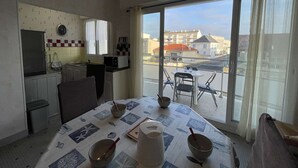 Ett kompakt kök med en matplats, utsikt över gatan och en balkong med ett bord och stolar.