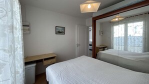 A bedroom with a bed, a desk, a mirror, and a window. - Cozy Beachside House: Ocean Views, Private Parking, Terrace, BBQ, Pets OK, Free Final Cleaning (Saint-Jean-de-Monts)