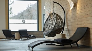 A modern interior with a large window, wicker chairs, and a hanging chair. - Sonnenresort Ettershaus (Bad Harzburg)