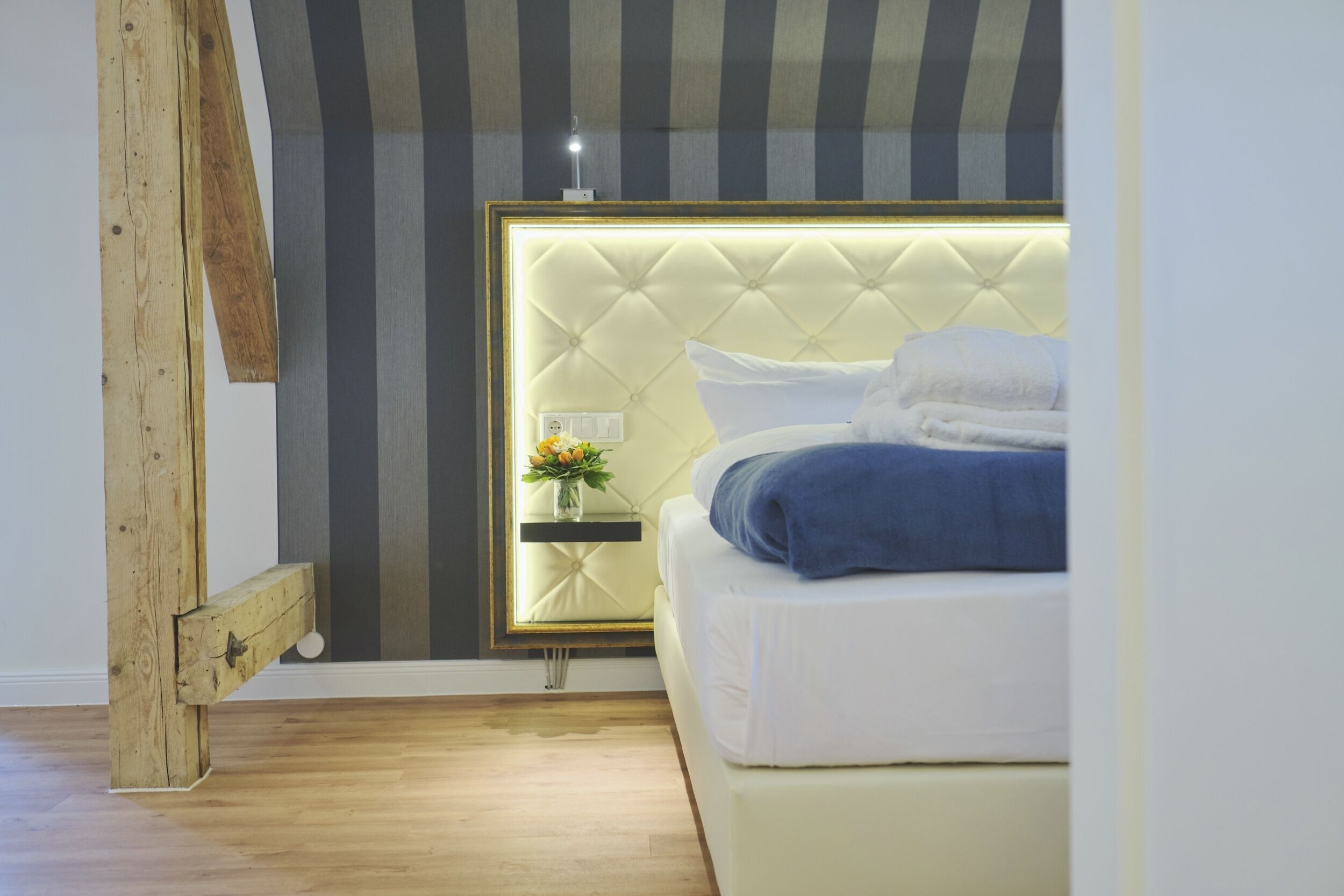 A bedroom with a bed, bedside table, and a mirror.
