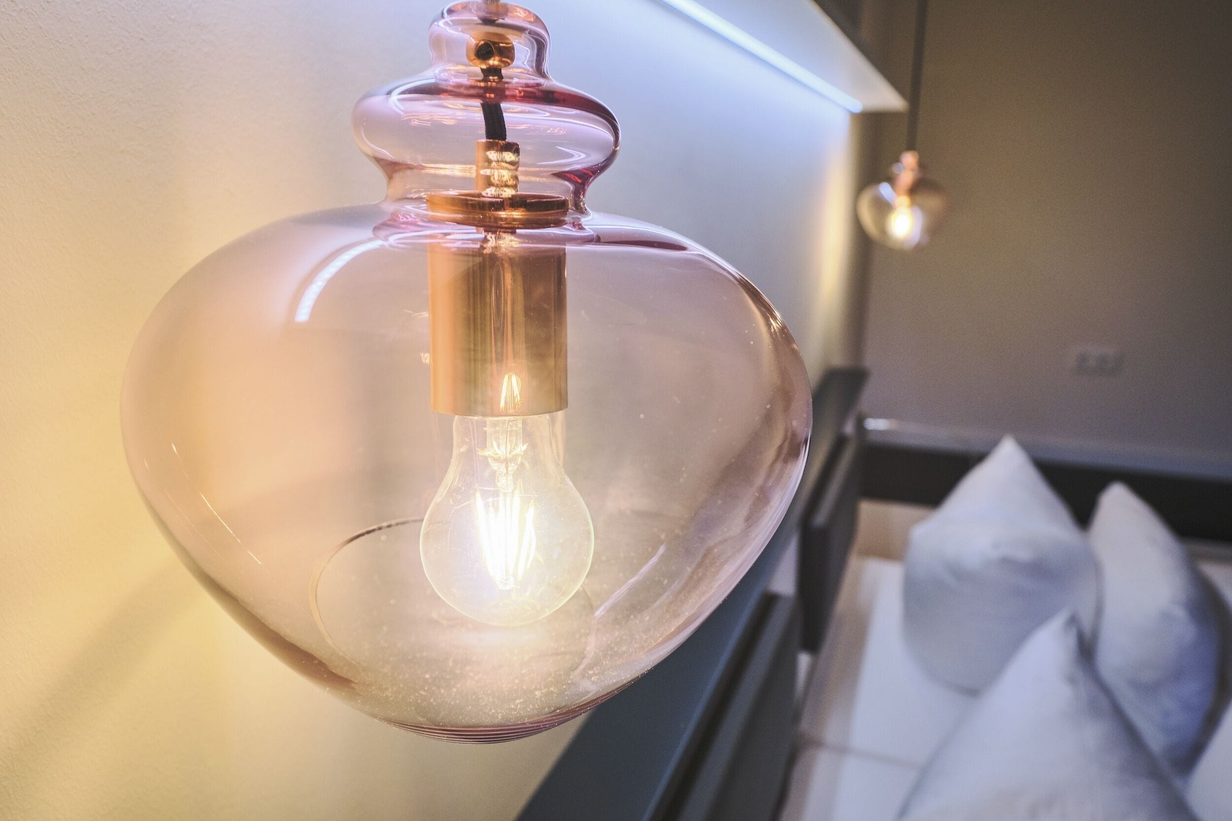 Una lámpara colgante de cristal transparente con una bombilla de filamento visible, suspendida del techo.
