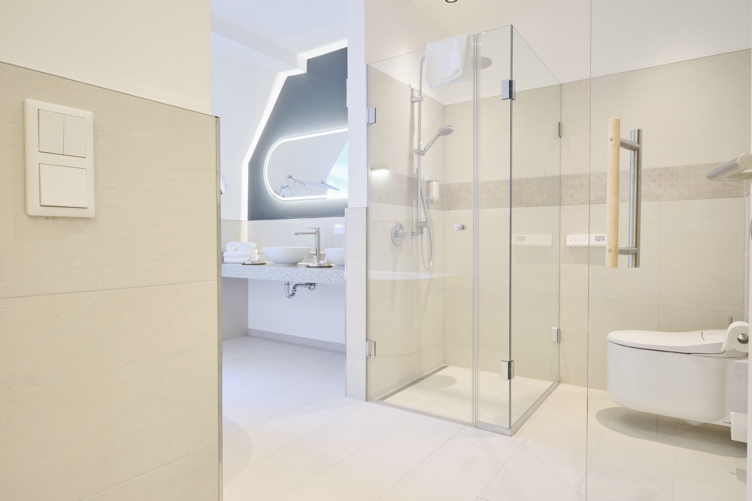 A modern bathroom with a glass shower enclosure, a toilet, and a sink area.