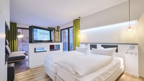 A modern hotel room with two beds, a TV, and a desk. - Sonnenresort Ettershaus (Bad Harzburg)