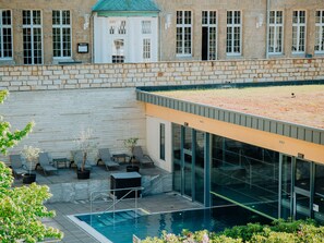 A modern building with a swimming pool, outdoor seating, and a rooftop garden. - Sonnenresort Ettershaus (Bad Harzburg)