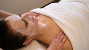 A person lying on a massage table with a white towel covering their upper body.