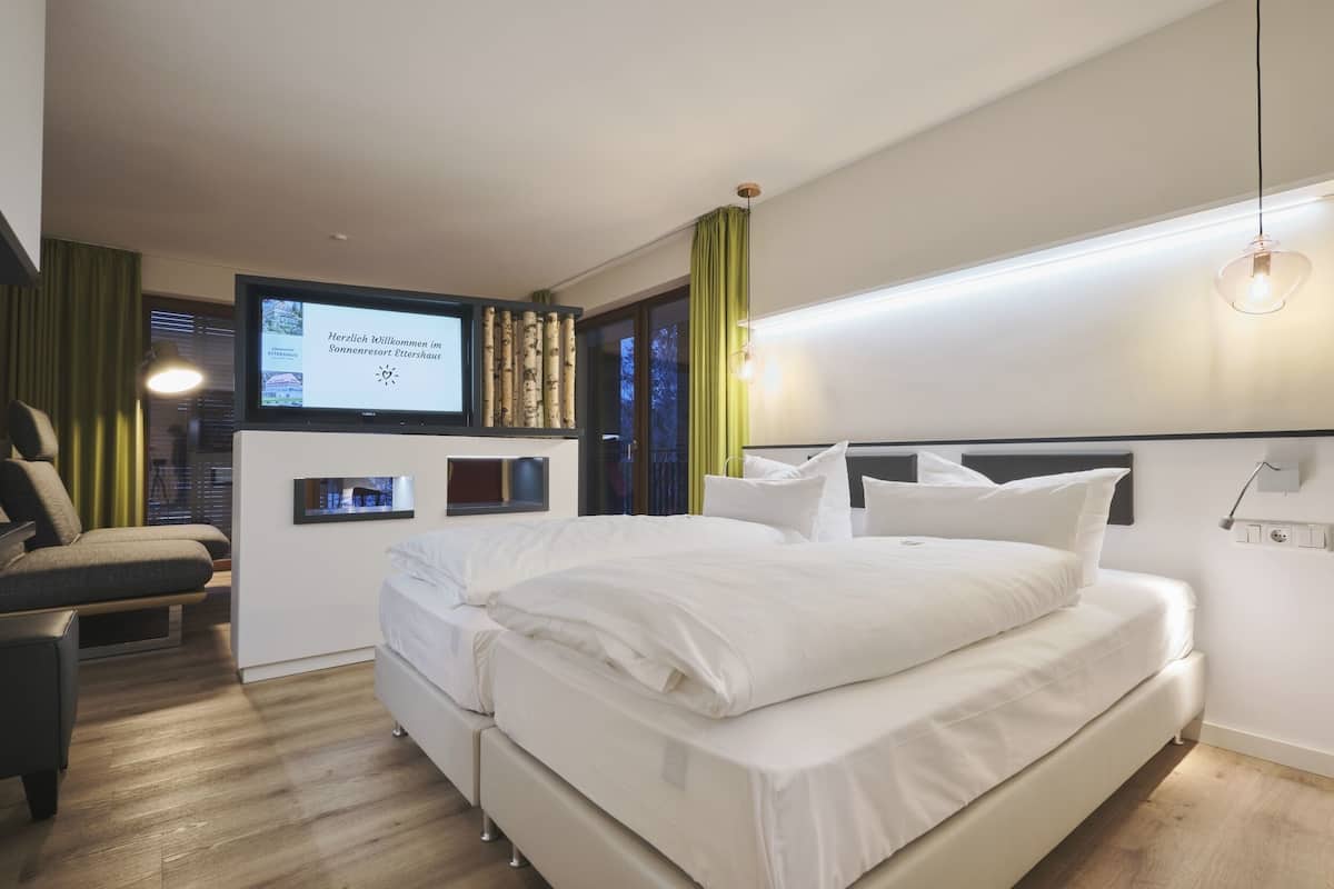 A modern hotel room with a bed, a desk, and a TV screen displaying a welcome message.