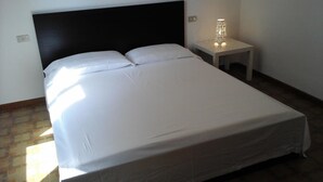 A neatly made bed with white linens in a room with a dark headboard and a bedside table with a lamp. - Bologna House (Perledo)