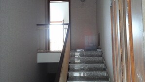 A staircase with a wooden handrail and a view of a room at the top. - Bologna House (Perledo)