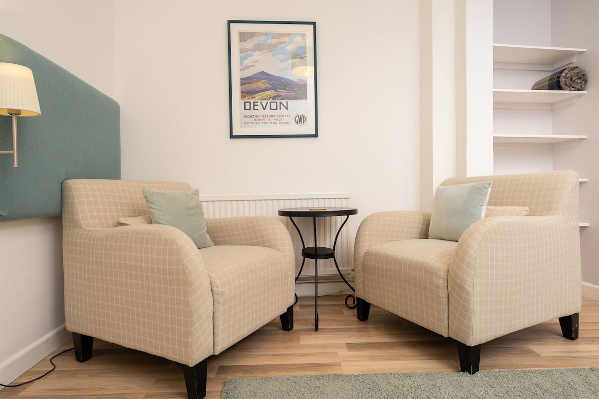 Une pièce comprenant deux fauteuils, une petite table ronde et un tableau encadré accroché au mur.