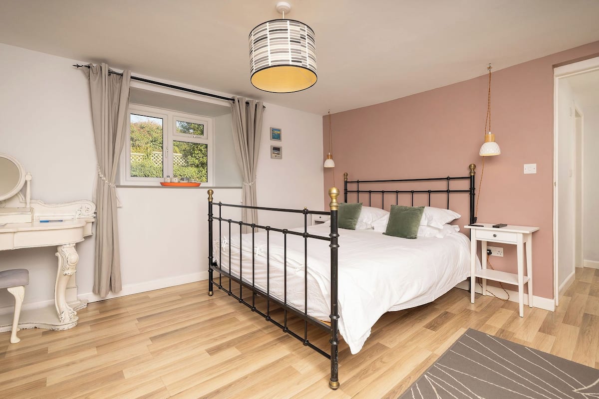 Une chambre à coucher avec un lit, une table de chevet, une lampe et une fenêtre avec des rideaux.