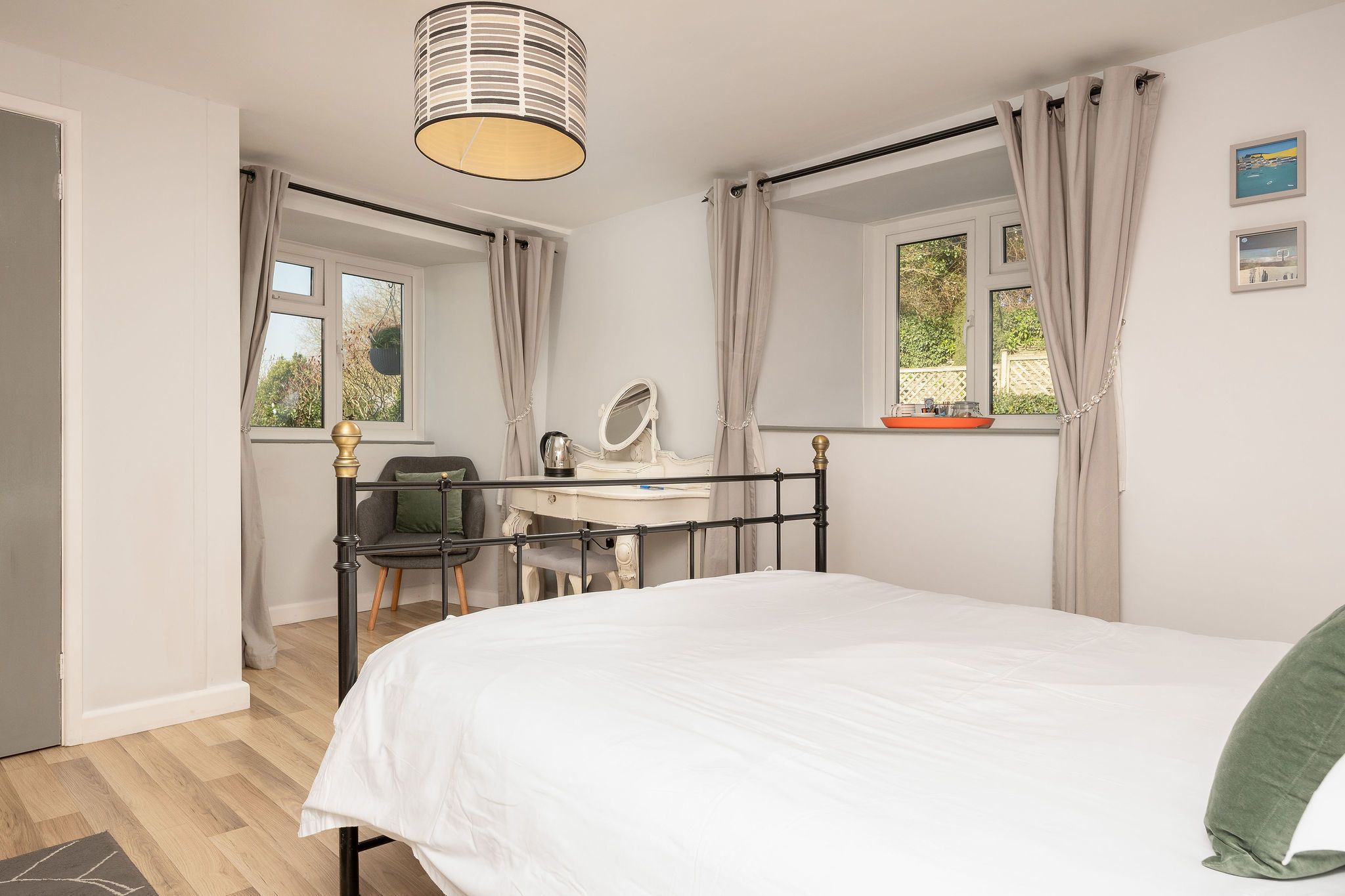 Une chambre à coucher avec un lit, un bureau avec une chaise, un miroir et une fenêtre avec des rideaux.