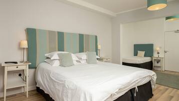 A bedroom with a large bed, two bedside tables, a nightstand, a mirror, and a hanging light fixture.