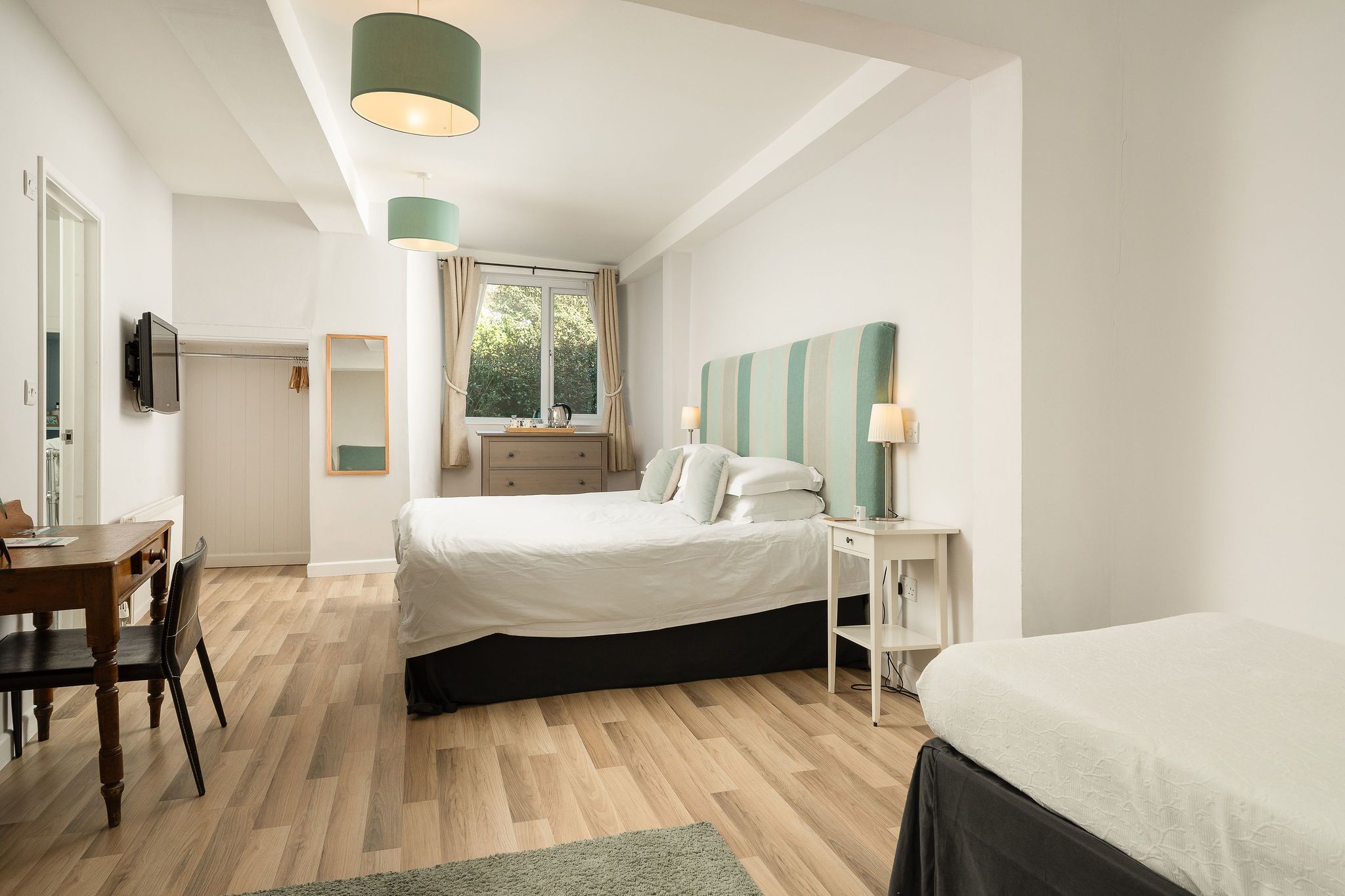 Une chambre à coucher avec un lit, une table de chevet, une lampe et une vue sur l’extérieur.