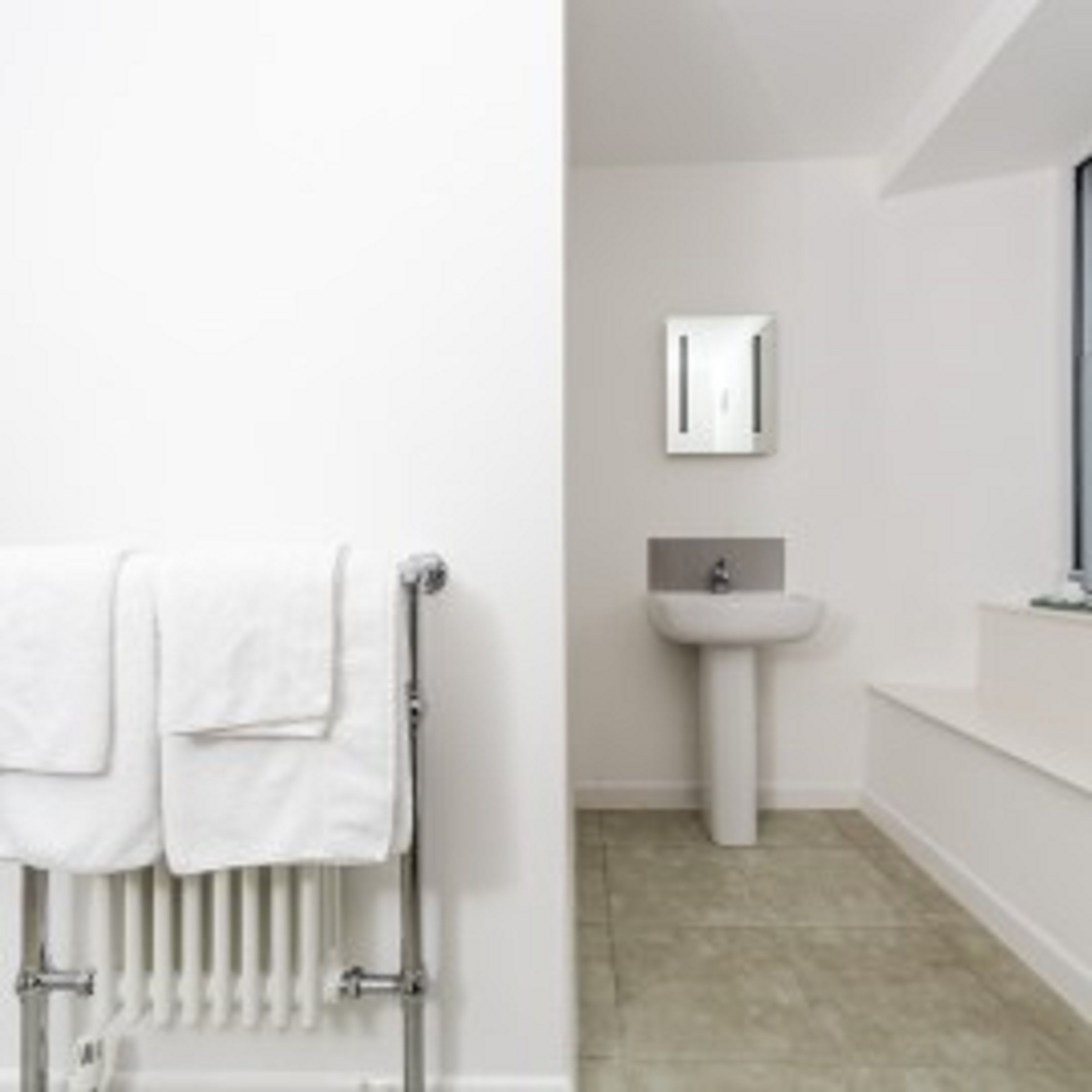 A bathroom with a white radiator, a sink, and a mirror.