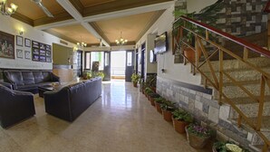A spacious living room with a leather sofa, a coffee table, and a fireplace with potted plants. - Kasang Regency Hill Resort (Lansdowne)