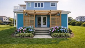 Une maison à deux étages dotée d’un porche abrité, d’une porte d’entrée et d’une pelouse bien entretenue agrémentée de parterres de fleurs.