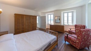 A bedroom with a bed, a wardrobe, a dresser, a chair, and two windows. - Villa Rachele (Varenna)