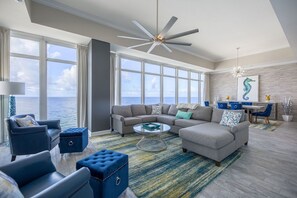 A spacious living room with a large window overlooking the ocean, a ceiling fan, and a modern interior design.