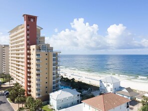 A coastal hotel with multiple floors, a beach view, and a pool area.