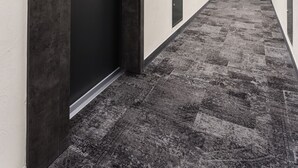 Un corridoio con pavimento in moquette, una porta con la scritta "201" e diverse porte lungo il corridoio.