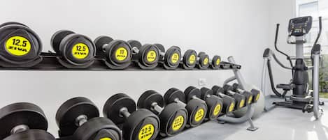 A gym with rows of dumbbells on racks, an exercise bike, and a treadmill.