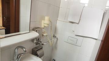 A bathroom with a sink, toilet, and a mirror.