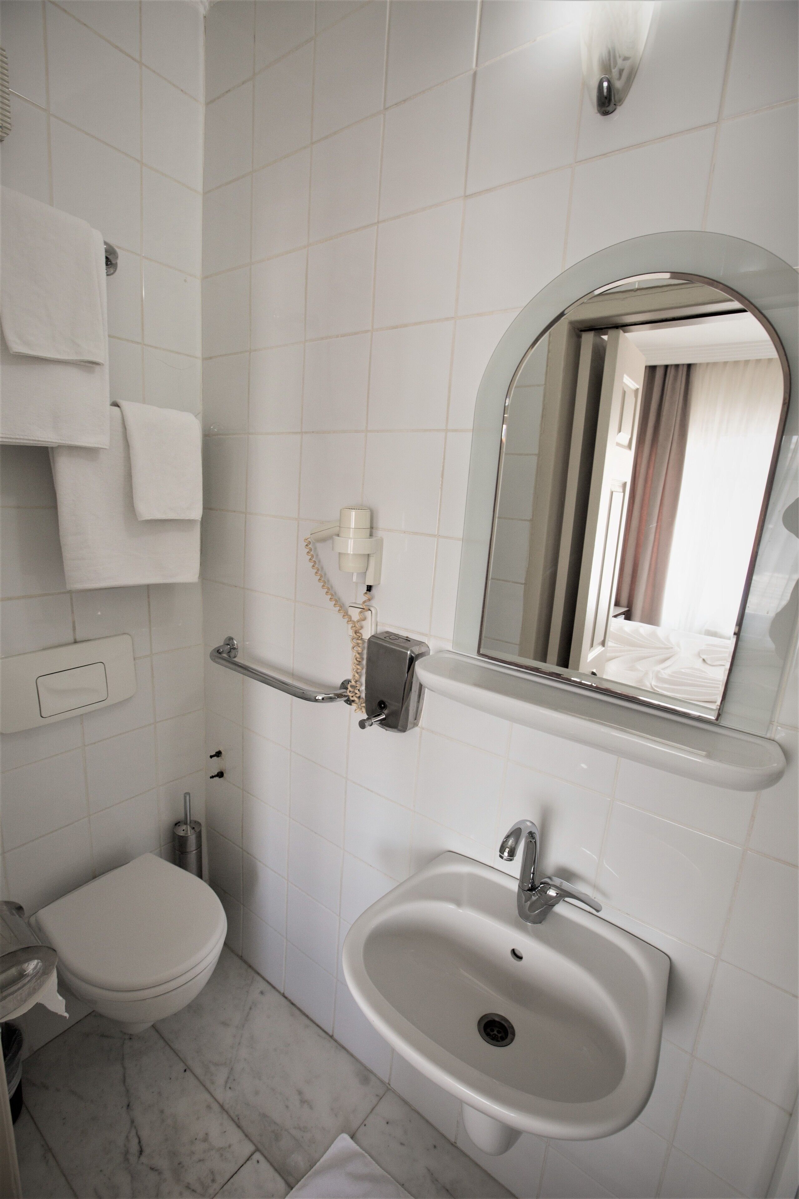 A bathroom with a toilet, sink, and mirror.