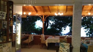 Un restaurante con vigas de madera en el techo, pared de ladrillo y vistas a árboles.