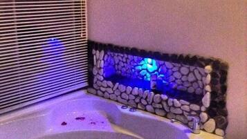 A bathroom with a bathtub, a stone wall, and a small framed picture on the wall.