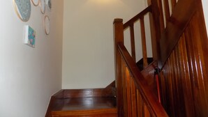 A wooden staircase with a handrail, a wall-mounted light fixture, and several framed artworks.