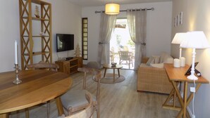A cozy living room with a wooden dining table, chairs, a sofa, and a TV.