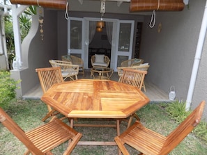 An outdoor patio with a wooden table and chairs, surrounded by a garden. - The Beach Retreat (Cap Malheureux)