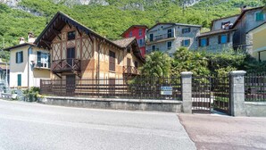 A traditional Alpine chalet with a wooden facade, a balcony, and a stone gate. - Villa La Rossa (Varenna)