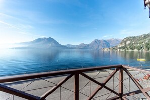 A lake with mountains in the background, a clear sky, and a metal railing in the foreground. - Villa La Rossa (Varenna)