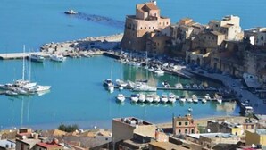 Une ville côtière dotée d’un château historique, d’un port de plaisance avec des bateaux et de bâtiments traditionnels.