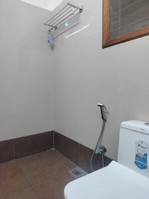 A bathroom with a shower, toilet, and a towel rack. - Hotel Ranjit Residency (Hyderabad)