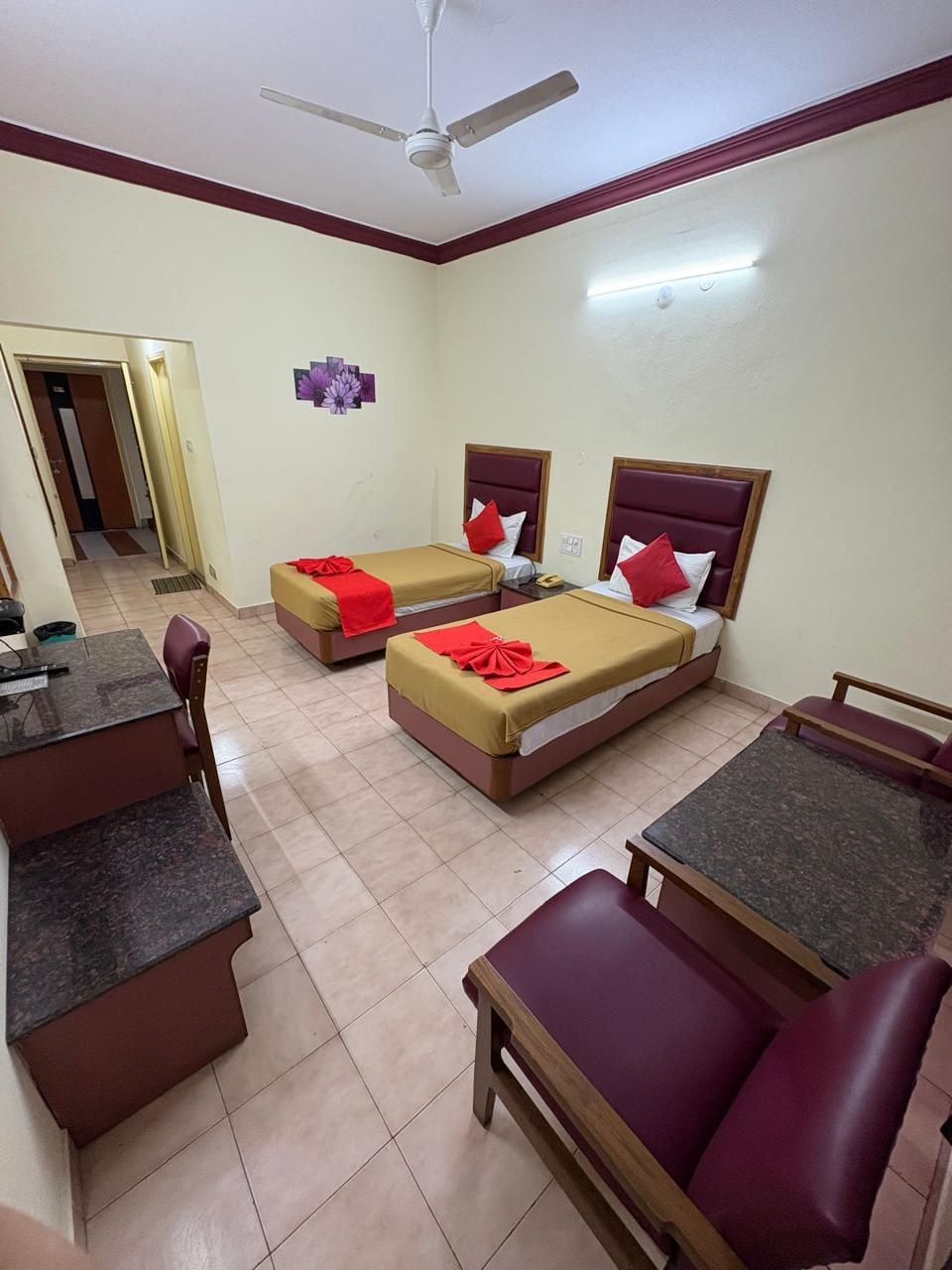 A hotel room with two single beds, a desk, and a seating area.