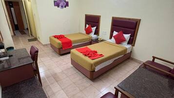A hotel room with two single beds, a desk, and a seating area.