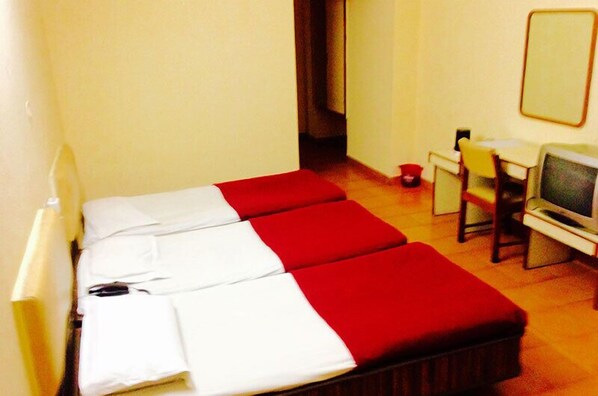 Una habitación pequeña con una cama, un escritorio, una silla y un televisor.