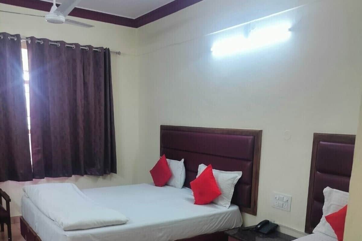 A hotel room with two single beds, a ceiling fan, and a window with curtains.
