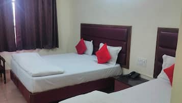 A hotel room with two single beds, a ceiling fan, and a window with curtains.