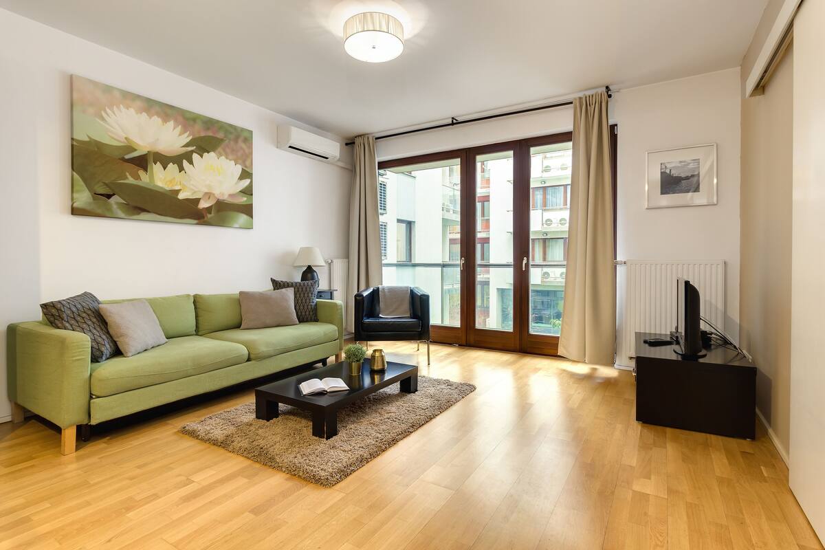 Una sala de estar moderna con un sofá verde, una mesita de centro y un cuadro de flores en la pared.
