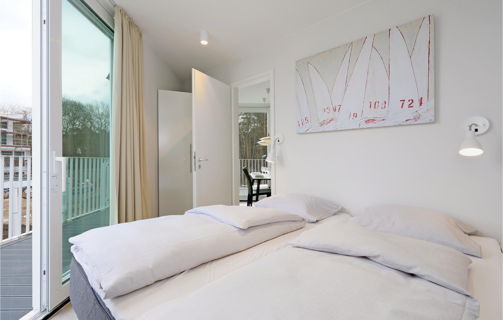 Een hotelkamer met twee bedden, een balkon en uitzicht.