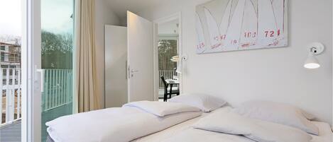 Een hotelkamer met twee bedden, een balkon en uitzicht.