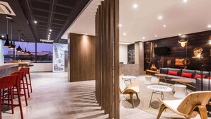 A modern interior with a bar area, seating, and a wall with travel-themed illustrations.