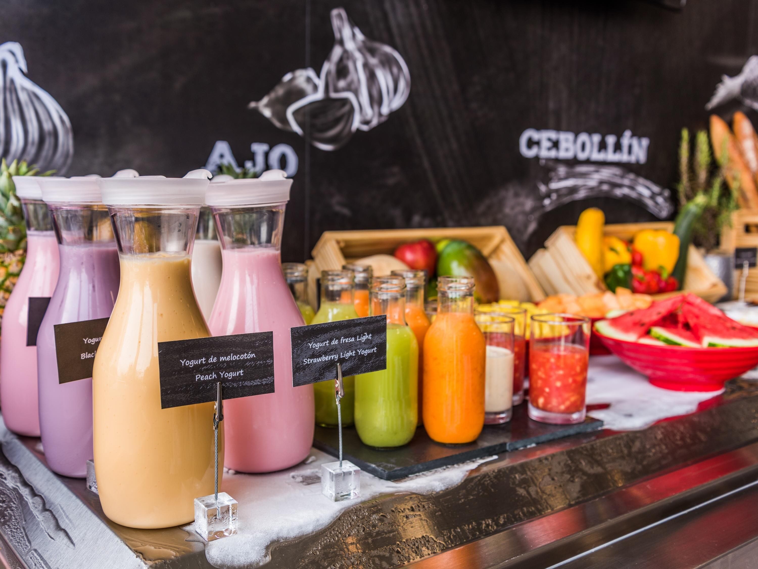 A beverage station with various drinks and fresh fruits.