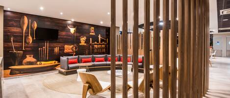 A modern interior with a wooden wall, a sofa with red cushions, and a television mounted on the wall.