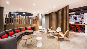 A modern lounge area with a curved sofa, white tables, and wooden chairs.