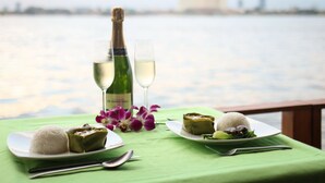 A table with a bottle of wine, two glasses, and plates of food by a waterfront.